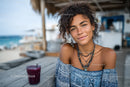 Young Woman Smiling at Beachside Cafe with Tropical Drink