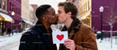 Couple sharing a tender kiss with Valentine card outdoors