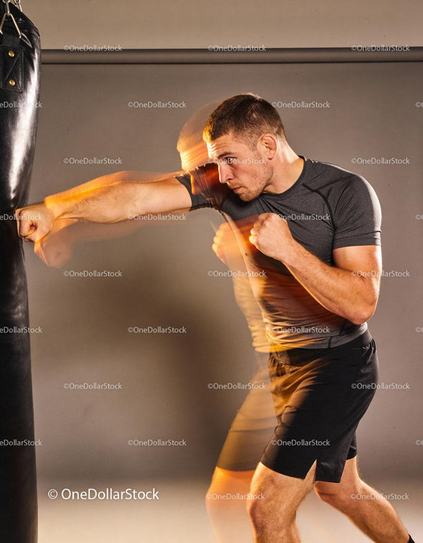 Man practicing powerful boxing punches on heavy bag