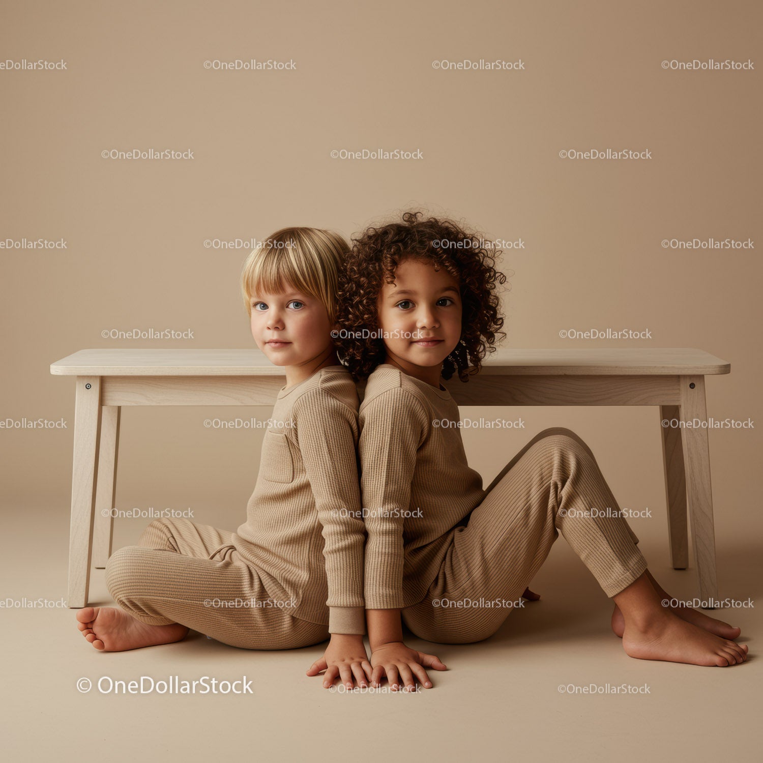 Two children sitting back to back near wooden bench