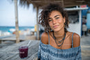 Young Woman Enjoying Refreshing Purple Drink at Beachside Cafe