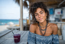 Young Woman Relaxing at Beachside Café with Fruit Drink