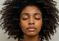 Close-up of a woman with curly hair and facial mask relaxing