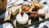 Assorted Cheese Board with Fruits and Honey on Picnic