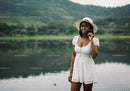 Beautiful Woman in White Dress with Wide-Brim Hat by Lake