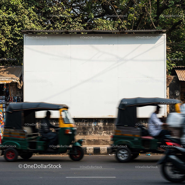 Street scene with blurred autorickshaws passing by white billboard JPG Mockup Image