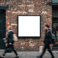 Two blurred pedestrians walking past blank billboard on brick wall