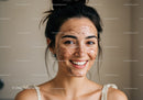 Young woman with facial mask demonstrating skincare routine
