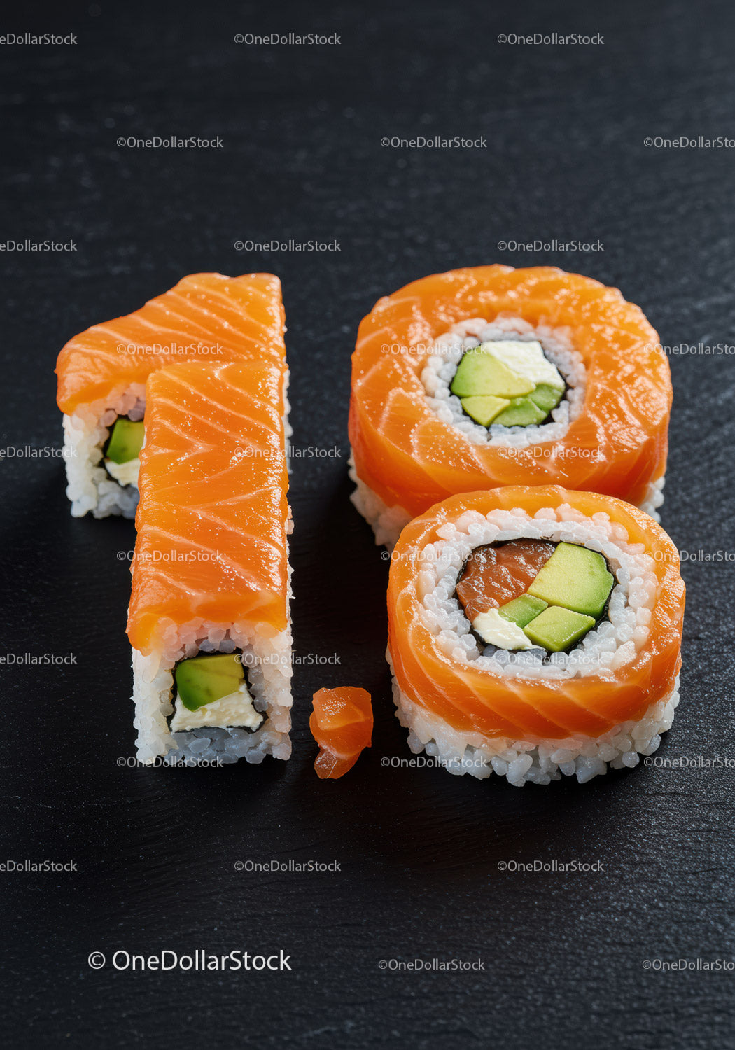 Rolki sushi z łososiem ułożone w kształcie dziesiątek na czarnej płycie łupkowej