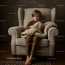 Young boy sitting calmly in cozy armchair with blanket