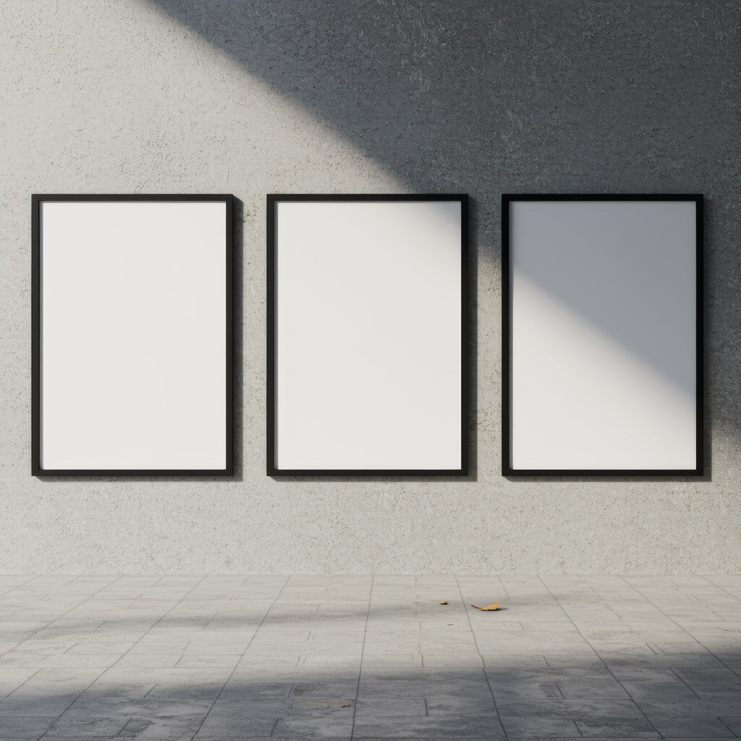 Three blank black frames on textured gray wall