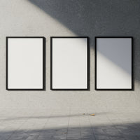 Three blank black frames on textured gray wall