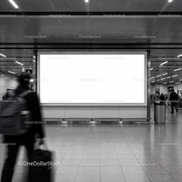 Traveler walking past blank advertising billboard in subway station