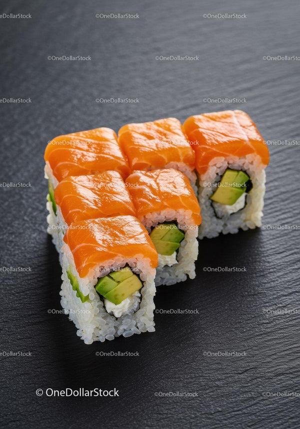 Fresh salmon avocado sushi rolls on dark surface