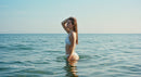 Young Woman in White Bikini Enjoying the Ocean Water on a Sunny Day