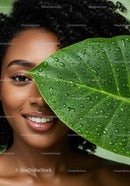 Beautiful Woman with Curly Hair and Water Droplets on Tropical Leaf