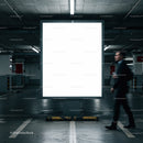 Man walking past illuminated blank billboard in parking garage