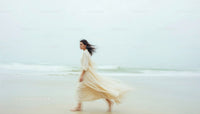 Graceful Woman Walking Along a Serene Beach at Dusk