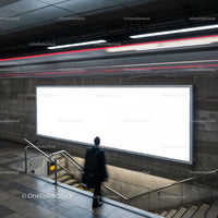 Person viewing bright blank billboard in urban subway station