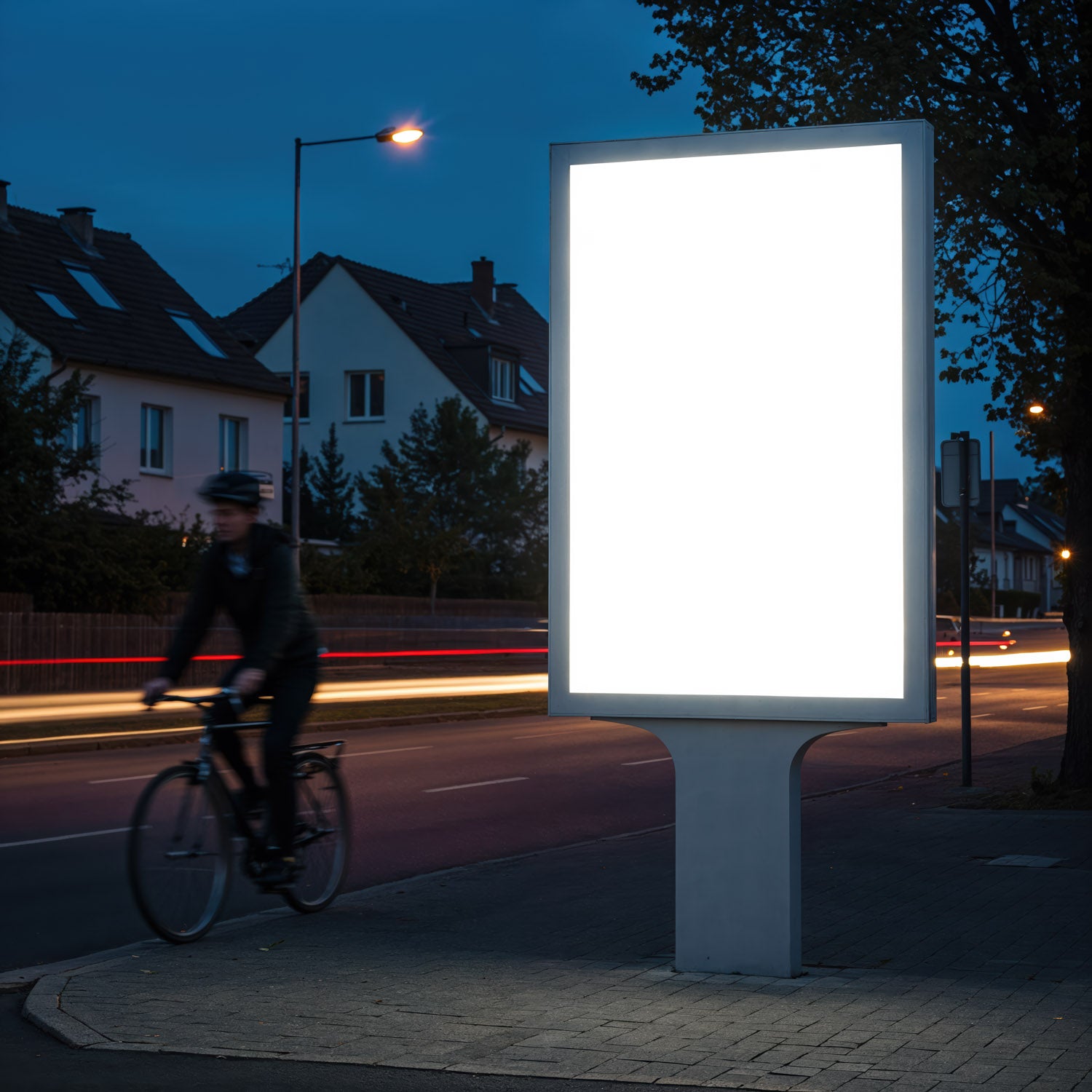 Illuminated blank billboard on city street at dusk