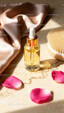 Natural facial oil with brush and rose petals on marble