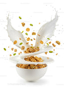 Golden cereal flakes and nuts splashing in milk bowl