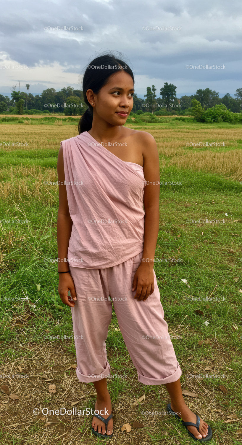 Young Woman in Pink Sari Standing Outdoors in Rural Green Fields
