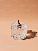 Frozen fig encased in clear ice block on beige surface