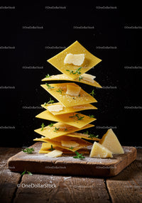 Stacked lasagna sheets with cheese and herbs on board
