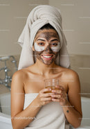 Young Woman with Facial Mask and Towel on Head Doing Skincare Routine