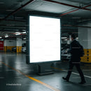 Businessman walking past illuminated billboard in parking garage