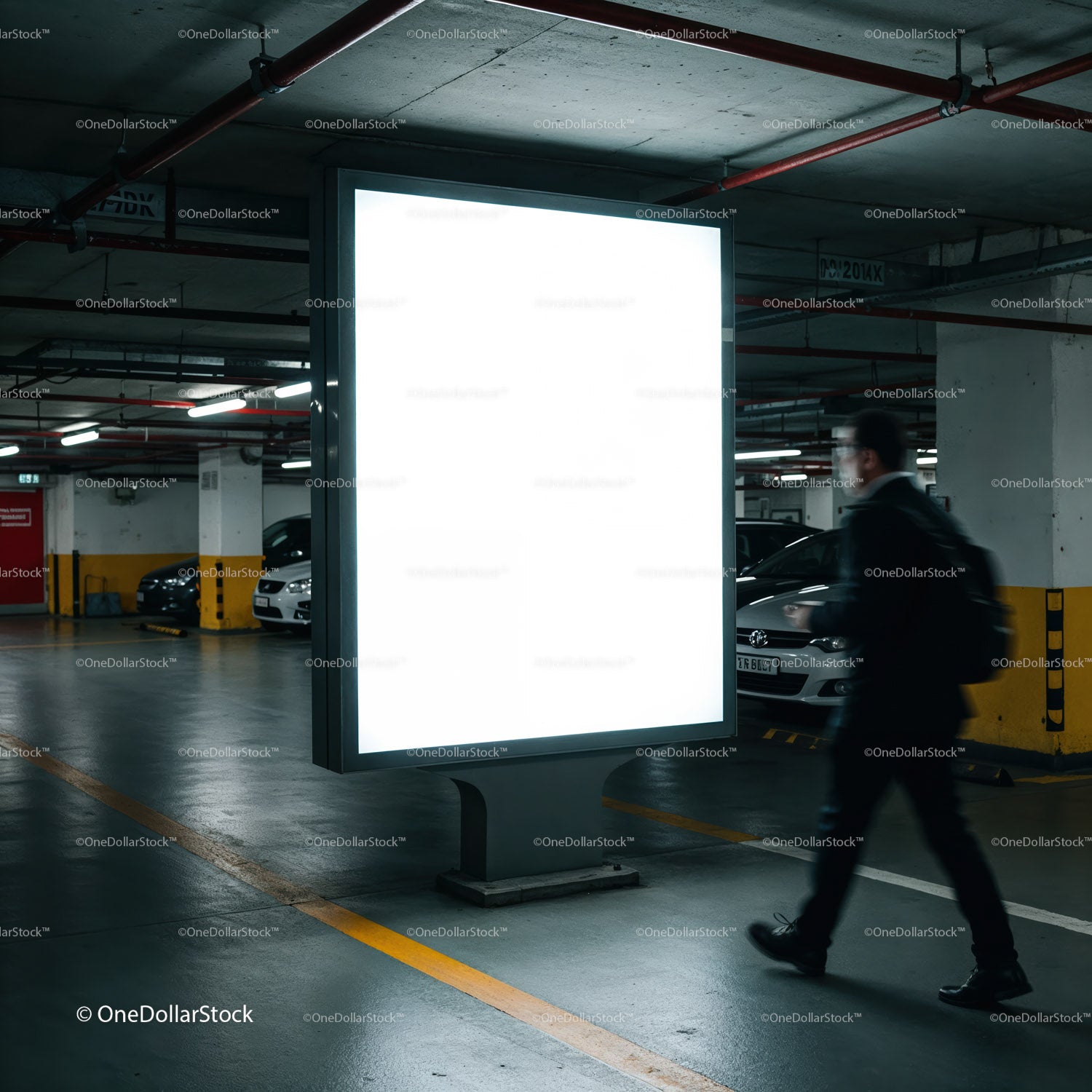 Businessman walking past illuminated billboard in parking garage