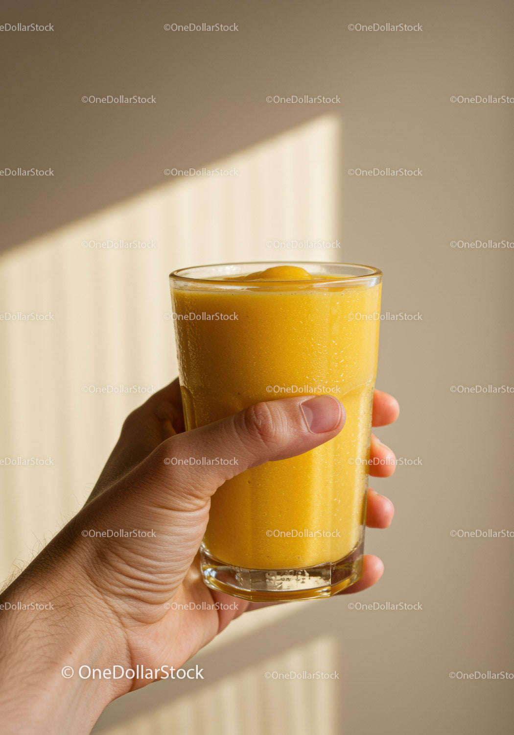 Hand holding a glass of fresh mango smoothie