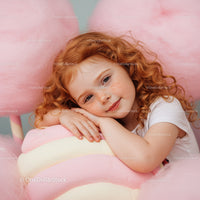 Smiling redhead girl resting on pastel candy decor