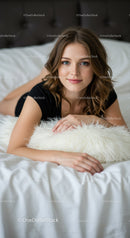 Young woman relaxing on bed with fluffy white pillow
