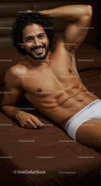 Smiling man relaxing on bed in white underwear