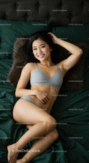Relaxed young woman lying on dark green bedding