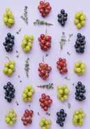 Colorful grape clusters and fresh thyme on pastel background