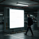 Man Walking Past Illuminated Billboard in Parking Garage