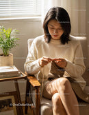 Woman knitting cozy scarf in sunlit room