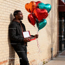 Man holding heart balloons and chocolates outdoor