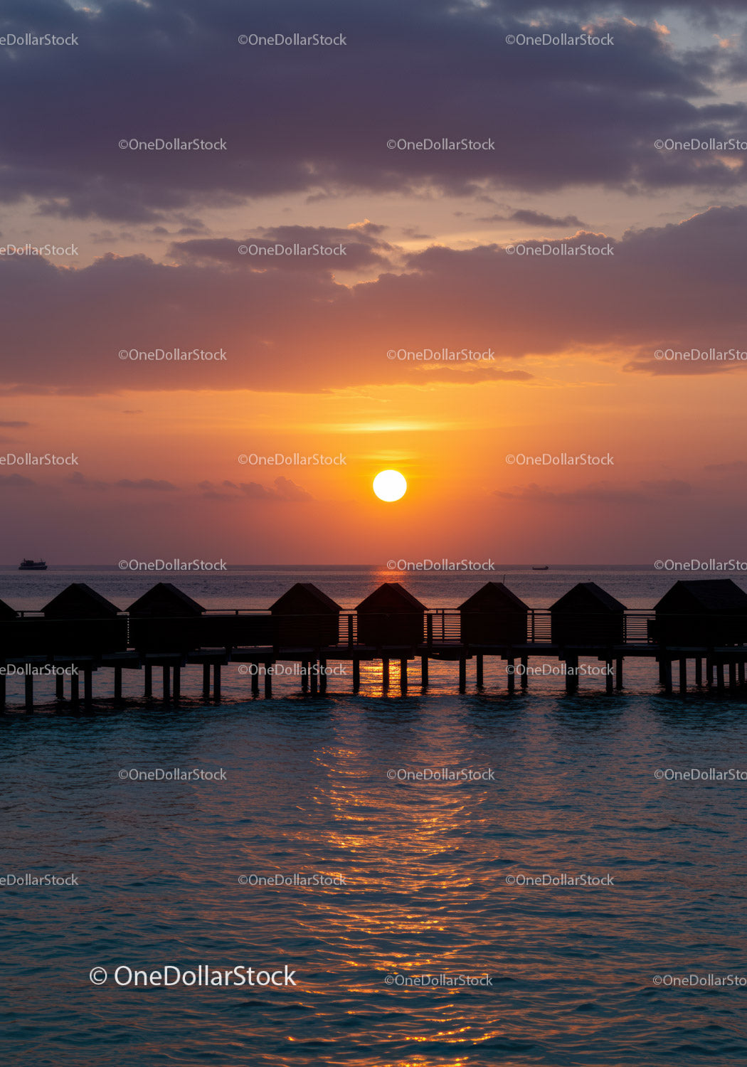 Beautiful Sunset Over Ocean with Overwater Bavilions in Tropical Paradise