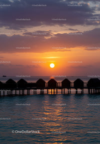 Beautiful Sunset Over Ocean with Overwater Bavilions in Tropical Paradise