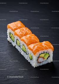 Fresh salmon avocado sushi rolls on slate board