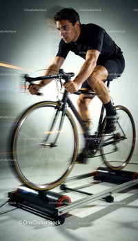 Focused cyclist training intensely on indoor roller trainer