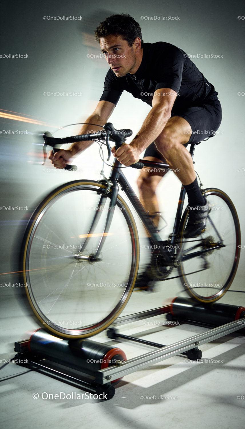 Focused cyclist training intensely on indoor roller trainer