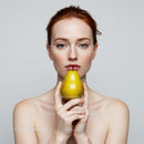 Young Woman with Blonde Hair Holding Yellow Pear in Front of Neutral Background