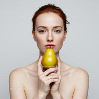 Young Woman with Blonde Hair Holding Yellow Pear in Front of Neutral Background