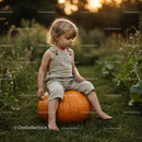 Young child sitting on large pumpkin in garden