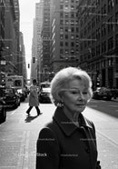 Elderly Woman in Busy City Street Surrounded by Vintage Cars